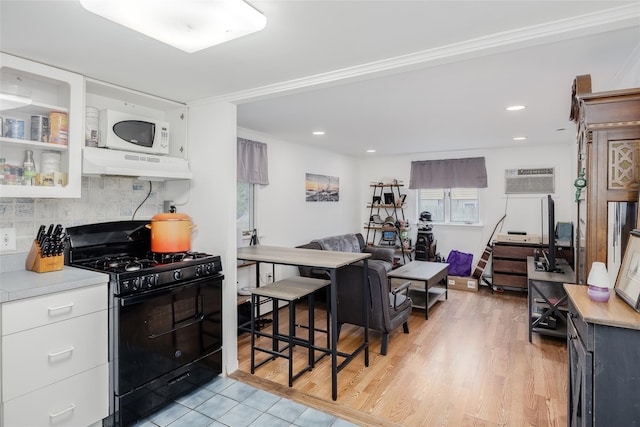 112 Middle Island Blvd, Middle Island, NY 11953 - kitchen featuring black range with gas cooktop, under cabinet range hood, white microwave, tasteful backsplash, and light countertops
