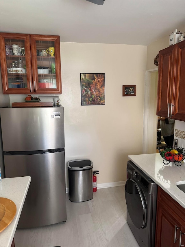 233-06 131st St Unit 1, Rosedale, NY 11412 - kitchen with freestanding refrigerator, washer / clothes dryer, glass insert cabinets, baseboards, and light floors