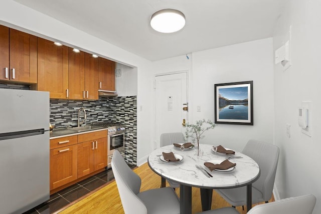 15 Oliver St Unit 3C, Brooklyn, NY 11209 - kitchen with appliances with stainless steel finishes, a sink, tasteful backsplash, under cabinet range hood, and brown cabinetry