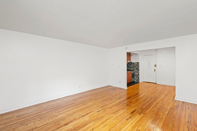 15 Oliver St Unit 3C, Brooklyn, NY 11209 - empty room featuring light wood finished floors, baseboards, and a wood stove