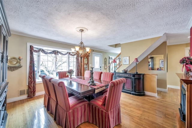 2193 Post St, East Meadow, NY 11554 - dining room featuring a chandelier, crown molding, light wood finished floors, stairs, and baseboards