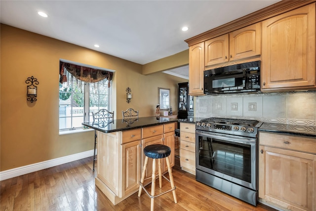 2193 Post St, East Meadow, NY 11554 - kitchen featuring gas range, black microwave, light brown cabinetry, a peninsula, and backsplash