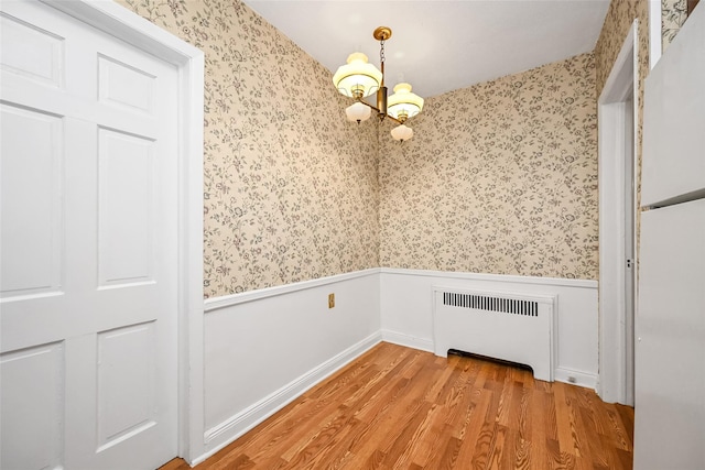 86-32 Avon St, Jamaica Estates, NY 11432 - unfurnished dining area featuring radiator, wallpapered walls, wainscoting, light wood-style floors, and a chandelier