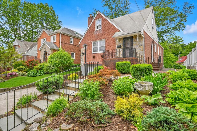 86-32 Avon St, Jamaica Estates, NY 11432 - view of front of house with stairs, a chimney, brick siding, and stone siding