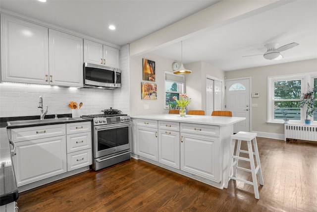 755 Webster Ave, New Rochelle, NY 10804 - kitchen featuring appliances with stainless steel finishes, a sink, a peninsula, radiator, and white cabinets