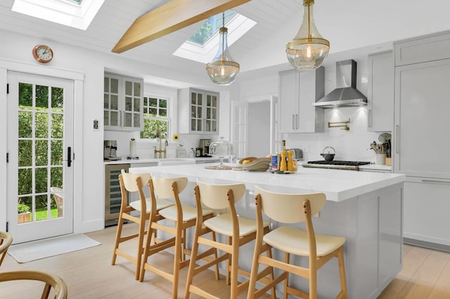 2 Longview Rd, Southampton, NY 11968 - kitchen featuring a skylight, wall chimney range hood, glass insert cabinets, a kitchen island, and a kitchen breakfast bar