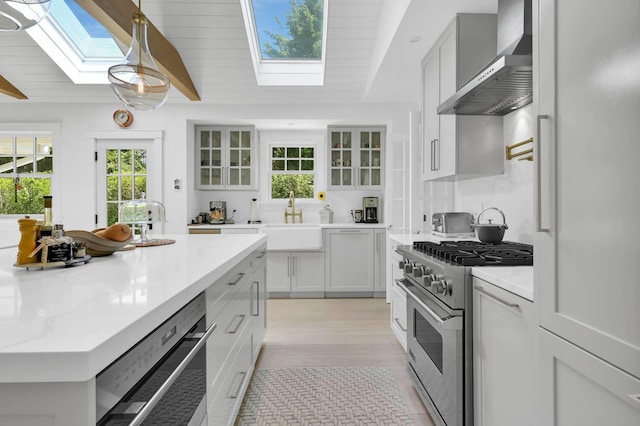 2 Longview Rd, Southampton, NY 11968 - kitchen with a skylight, high end stainless steel range oven, wall chimney exhaust hood, healthy amount of natural light, and beamed ceiling