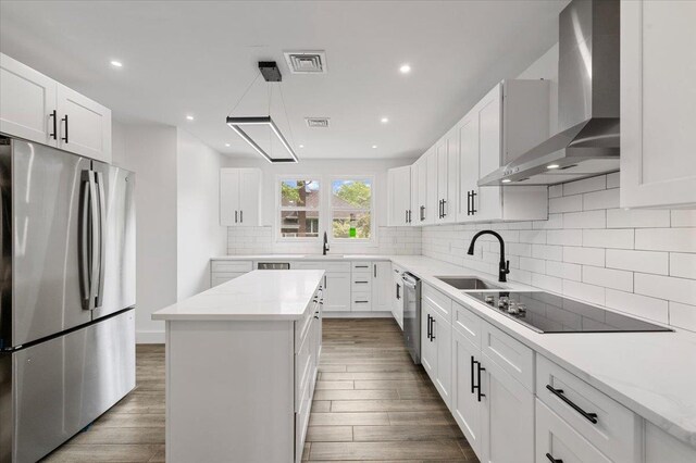 559 Linda Ln, Woodmere, NY 11598 - kitchen featuring stainless steel appliances, a sink, wall chimney exhaust hood, wood finished floors, and decorative backsplash