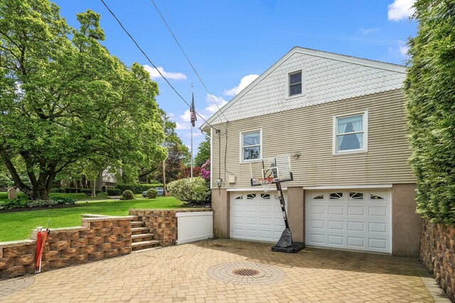 114 Longview Ave, White Plains, NY 10605 - view of side of property featuring an attached garage, stucco siding, decorative driveway, and a yard