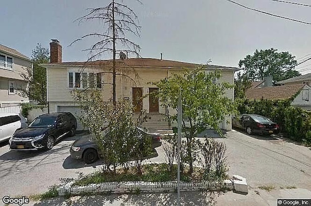 569 Peninsula Blvd, Cedarhurst, NY 11516 - view of front of house with driveway, a garage, and a chimney