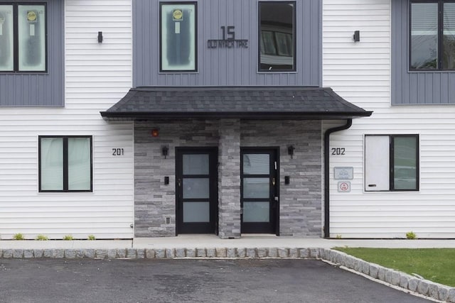 15 Old Nyack Tpke Unit 201, Monsey, NY 10952 - property entrance featuring stone siding, a shingled roof, and covered porch