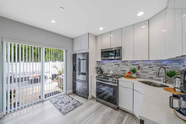 4 Cari Ln, Middle Island, NY 11953 - kitchen featuring stainless steel appliances, a sink, light wood-style flooring, backsplash, and modern cabinets