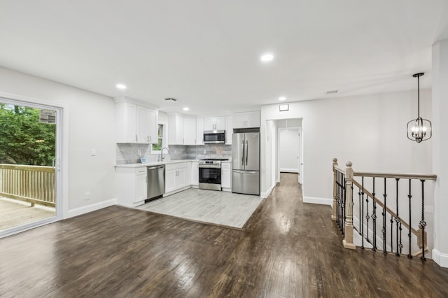 23 Tower St, Huntington Station, NY 11746 - kitchen with stainless steel appliances, wood finished floors, white cabinets, decorative backsplash, and light countertops