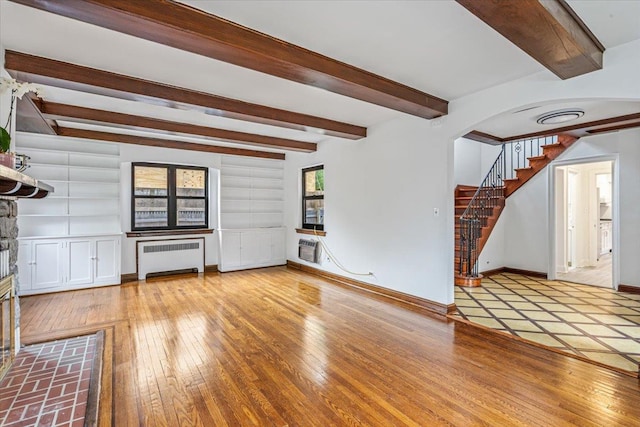 164-03 33rd Ave, Flushing, NY 11358 - unfurnished living room featuring radiator heating unit, beam ceiling, light wood finished floors, a wall unit AC, and stairs