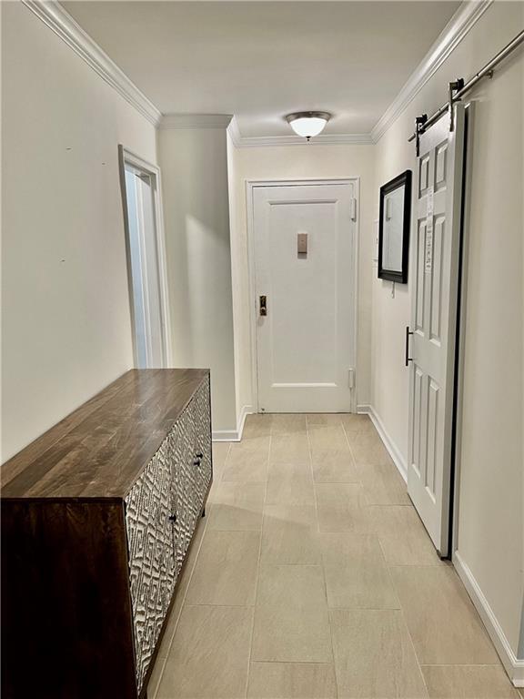 330 S Broadway Unit E2, Tarrytown, NY 10591 - hallway with ornamental molding, a barn door, baseboards, and light tile patterned flooring