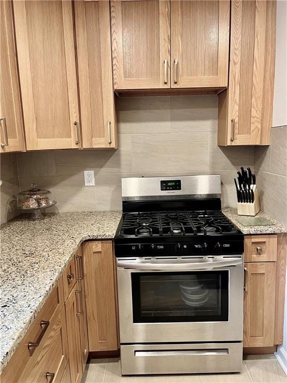330 S Broadway Unit E2, Tarrytown, NY 10591 - kitchen with gas stove, backsplash, light stone counters, and light tile patterned floors