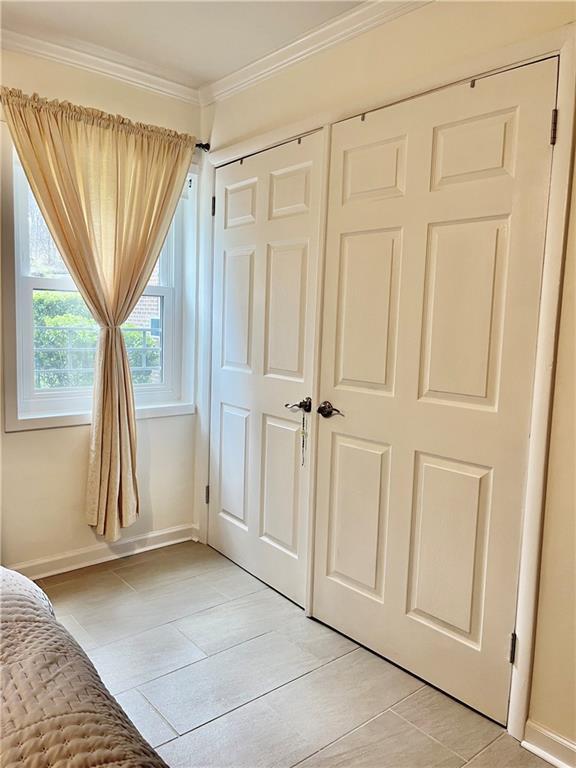 330 S Broadway Unit E2, Tarrytown, NY 10591 - unfurnished bedroom with ornamental molding, light tile patterned floors, baseboards, and a closet