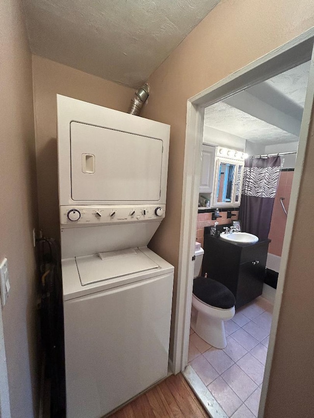 199-58 21st Ave Unit 1-165, Whitestone, NY 11357 - laundry area with stacked washer / dryer, light wood-style floors, and a textured ceiling