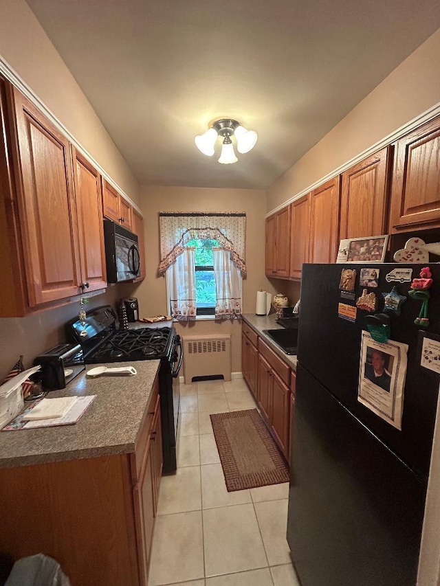 199-58 21st Ave Unit 1-165, Whitestone, NY 11357 - kitchen with black appliances, radiator heating unit, light tile patterned flooring, dark countertops, and brown cabinets