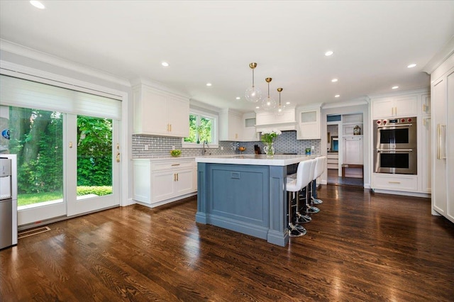 14 Pond Park Rd, Great Neck, NY 11023 - kitchen with stainless steel double oven, light countertops, white cabinets, backsplash, and crown molding