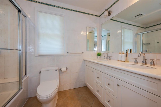 14 Pond Park Rd, Great Neck, NY 11023 - full bath featuring double vanity, toilet, shower / bath combination with glass door, tile patterned floors, and tile walls