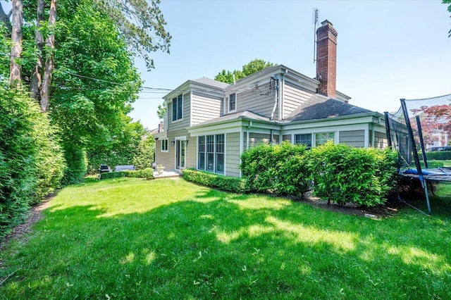 14 Pond Park Rd, Great Neck, NY 11023 - back of house with a trampoline, a chimney, and a lawn