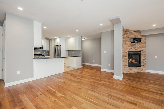 661 W Broadway Unit 203, Long Beach, NY 11561 - kitchen featuring appliances with stainless steel finishes, open floor plan, dark countertops, decorative backsplash, and white cabinets