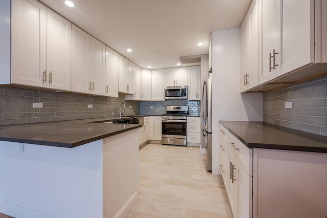 661 W Broadway Unit 203, Long Beach, NY 11561 - kitchen featuring stainless steel appliances, a peninsula, decorative backsplash, dark countertops, and recessed lighting