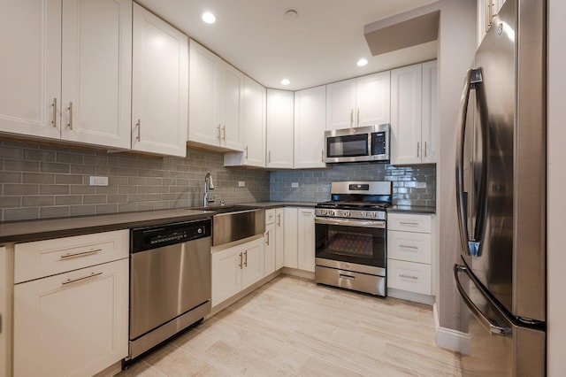661 W Broadway Unit 203, Long Beach, NY 11561 - kitchen featuring appliances with stainless steel finishes, a sink, dark countertops, backsplash, and white cabinetry