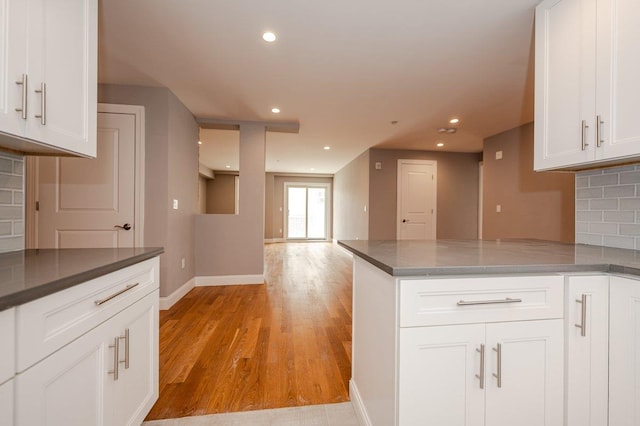 661 W Broadway Unit 203, Long Beach, NY 11561 - kitchen featuring baseboards, a peninsula, decorative backsplash, white cabinetry, and light wood-style floors