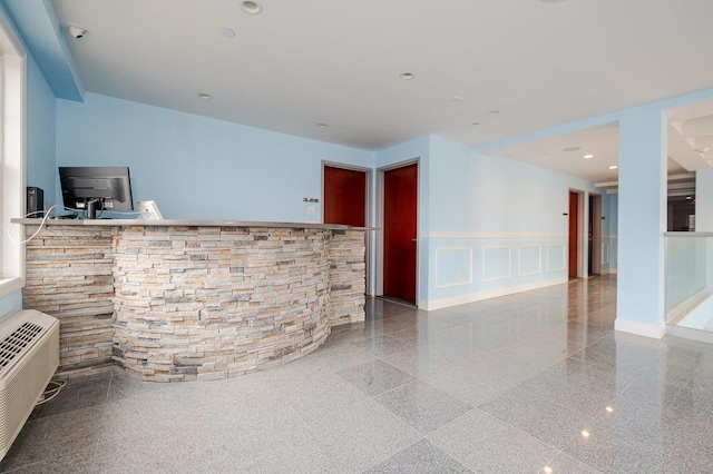 661 W Broadway Unit 203, Long Beach, NY 11561 - unfurnished living room featuring granite floors, a decorative wall, and wainscoting