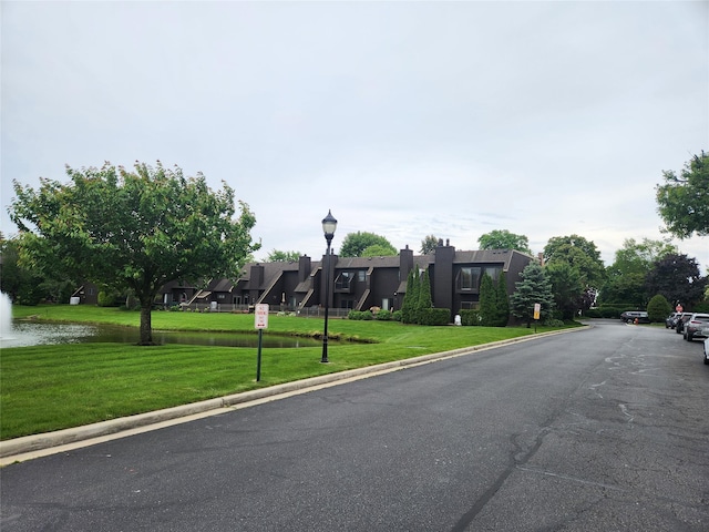 166 Southgate Cir, Massapequa Park, NY 11762 - view of asphalt street featuring a water view, street lights, curbs, a residential view, and traffic signs