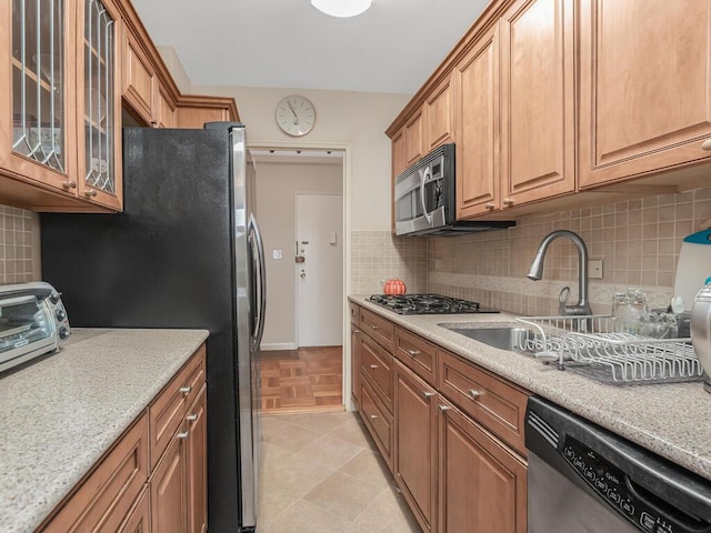 5550 Fieldston Rd Unit 8D, Bronx, NY 10471 - kitchen featuring appliances with stainless steel finishes, decorative backsplash, glass insert cabinets, a sink, and light stone counters