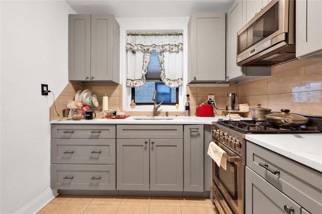150 W End Ave Unit 1J, Brooklyn, NY 11235 - kitchen featuring appliances with stainless steel finishes, gray cabinetry, a sink, backsplash, and light countertops
