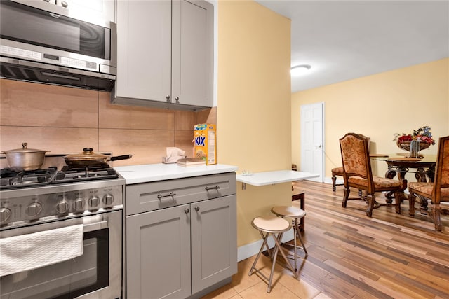 150 W End Ave Unit 1J, Brooklyn, NY 11235 - kitchen featuring stainless steel appliances, gray cabinets, tasteful backsplash, light countertops, and light wood-style floors