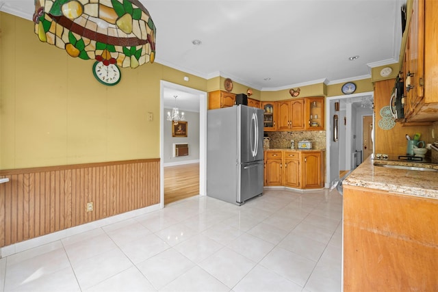 613 Gary Pl, Westbury, NY 11590 - kitchen with stainless steel appliances, brown cabinetry, a chandelier, decorative backsplash, and light stone counters