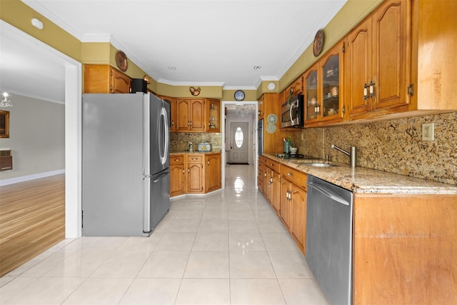 613 Gary Pl, Westbury, NY 11590 - kitchen featuring stainless steel appliances, a sink, brown cabinets, ornamental molding, and light stone counters