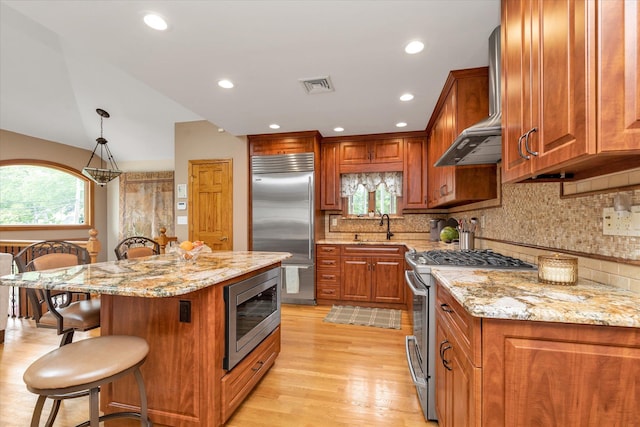 314 Oakview Ave, Oceanside, NY 11572 - kitchen with built in appliances, wall chimney exhaust hood, a kitchen breakfast bar, a sink, and brown cabinets