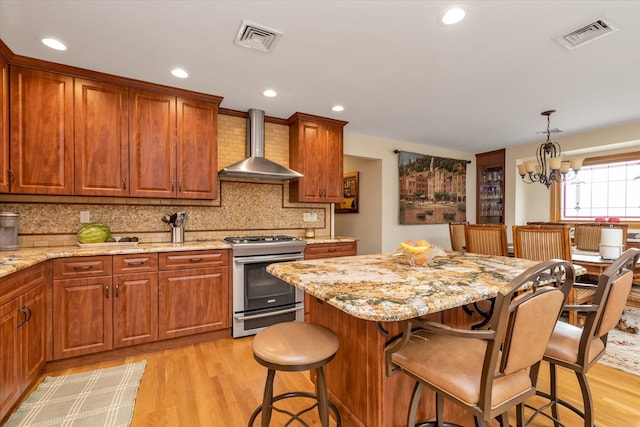314 Oakview Ave, Oceanside, NY 11572 - kitchen featuring stainless steel range with gas cooktop, wall chimney exhaust hood, light wood-style flooring, a breakfast bar area, and decorative backsplash