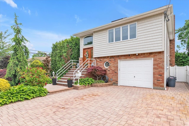 314 Oakview Ave, Oceanside, NY 11572 - view of front of home with brick siding, an attached garage, decorative driveway, and a gate