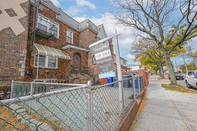 90-28 Pitkin Ave, Ozone Park, NY 11417 - view of front of home featuring brick siding, a fenced front yard, and mansard roof