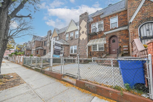 90-28 Pitkin Ave, Ozone Park, NY 11417 - townhome / multi-family property featuring a residential view, brick siding, a fenced front yard, and a high end roof