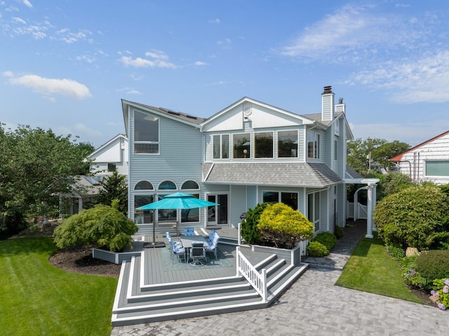 1416 Bay Blvd, Atlantic Beach, NY 11509 - rear view of property with a chimney, outdoor dining area, a lawn, a wooden deck, and a shingled roof