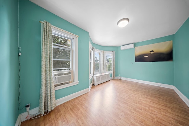 8564 79th St, Woodhaven, NY 11421 - empty room featuring an AC wall unit, healthy amount of natural light, baseboards, and wood finished floors