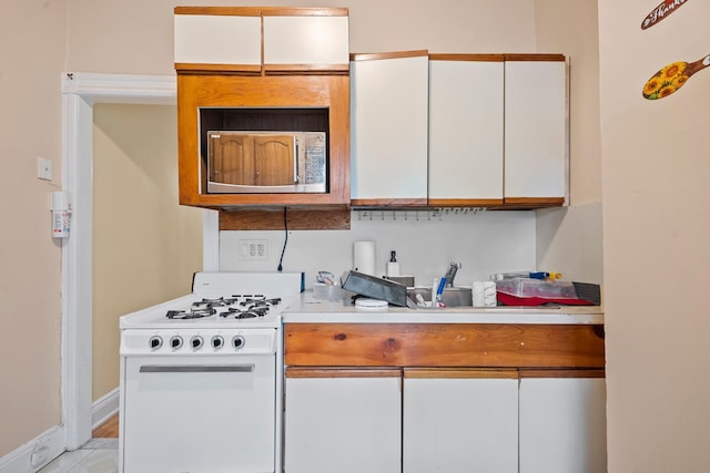 8564 79th St, Woodhaven, NY 11421 - kitchen with white gas range oven, light countertops, white cabinetry, baseboards, and stainless steel microwave