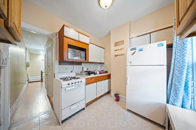 8564 79th St, Woodhaven, NY 11421 - kitchen with white appliances, light countertops, baseboards, and white cabinetry