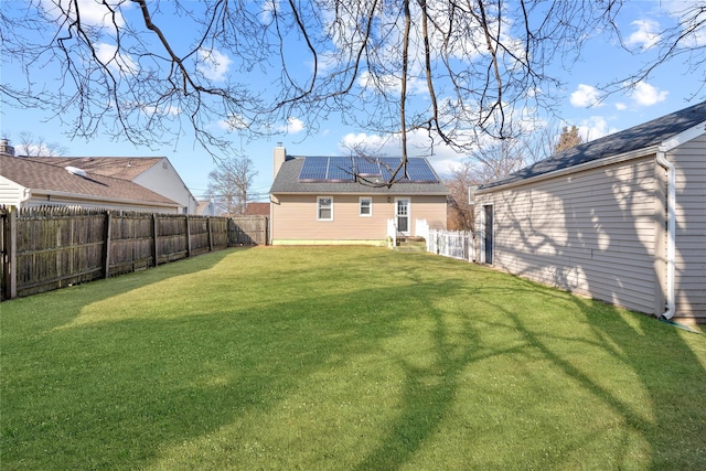 49 Anderson Ave, North Babylon, NY 11703 - rear view of property featuring roof mounted solar panels and a chimney