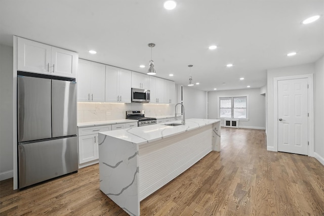 4163 Laconia Ave, Bronx, NY 10466 - kitchen with stainless steel appliances, a sink, white cabinets, an island with sink, and decorative backsplash