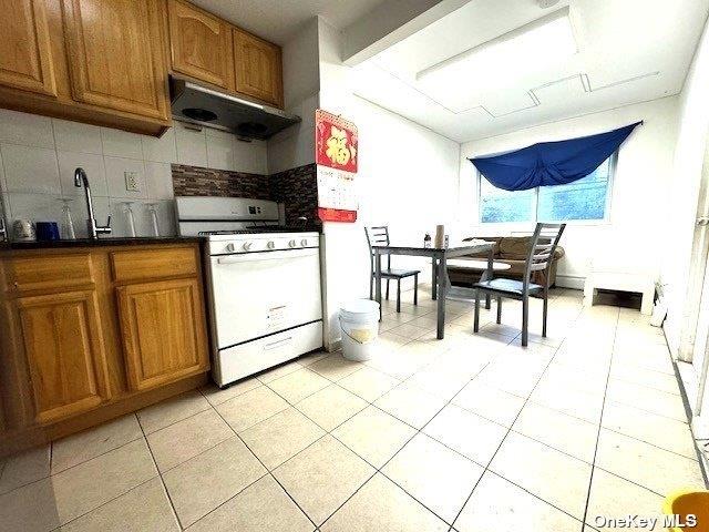 94-68 45th Ave, Elmhurst, NY 11373 - kitchen with white gas range oven, ventilation hood, brown cabinets, and backsplash