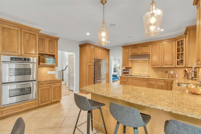 6 Esteves Ct, Melville, NY 11747 - kitchen featuring stainless steel appliances, a sink, under cabinet range hood, a peninsula, and light stone countertops